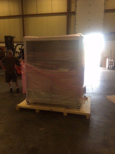 Wrapped pallet in warehouse with bright doorway and a person standing to the left