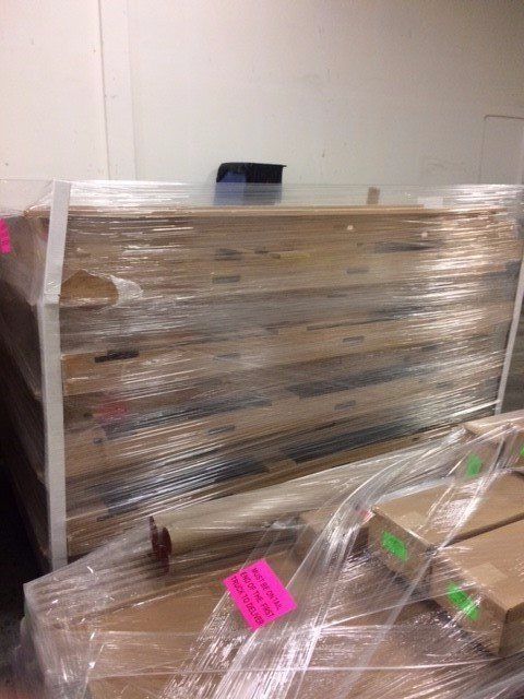 Plastic-wrapped wooden furniture and boxes stacked in a storage room