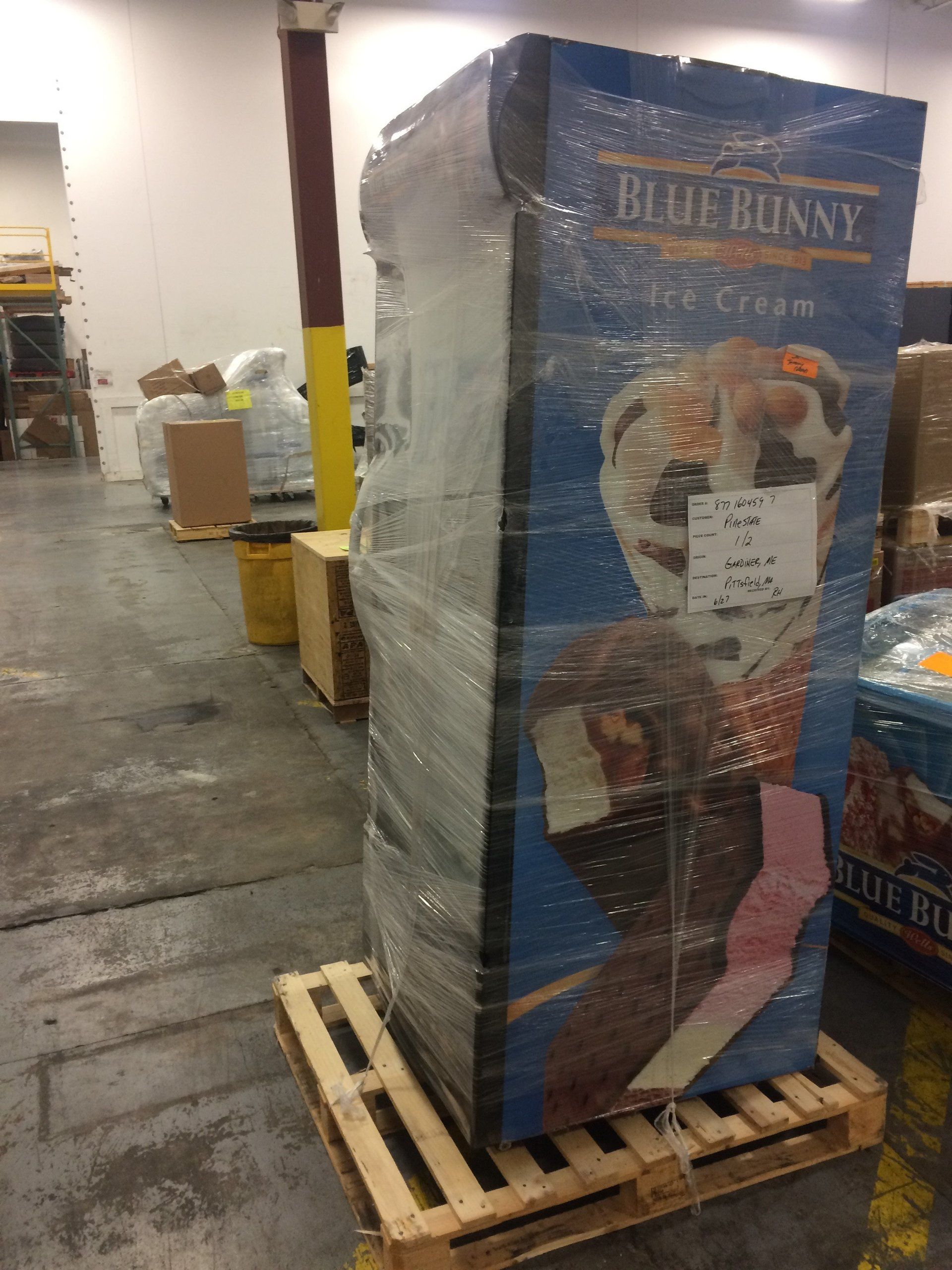 Shrink-wrapped Blue Bunny ice cream display on a pallet in a warehouse aisle.