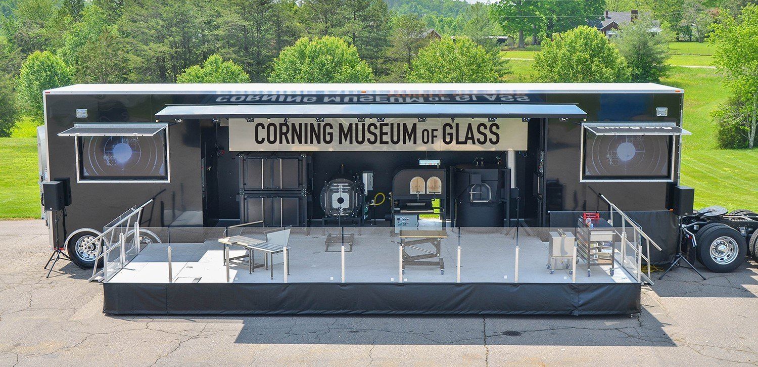 Corning Museum of Glass mobile exhibit trailer with black sides and glass displays parked outdoors