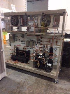 Open industrial control cabinet with wiring, gauges, fans, and mechanical components on a workshop floor