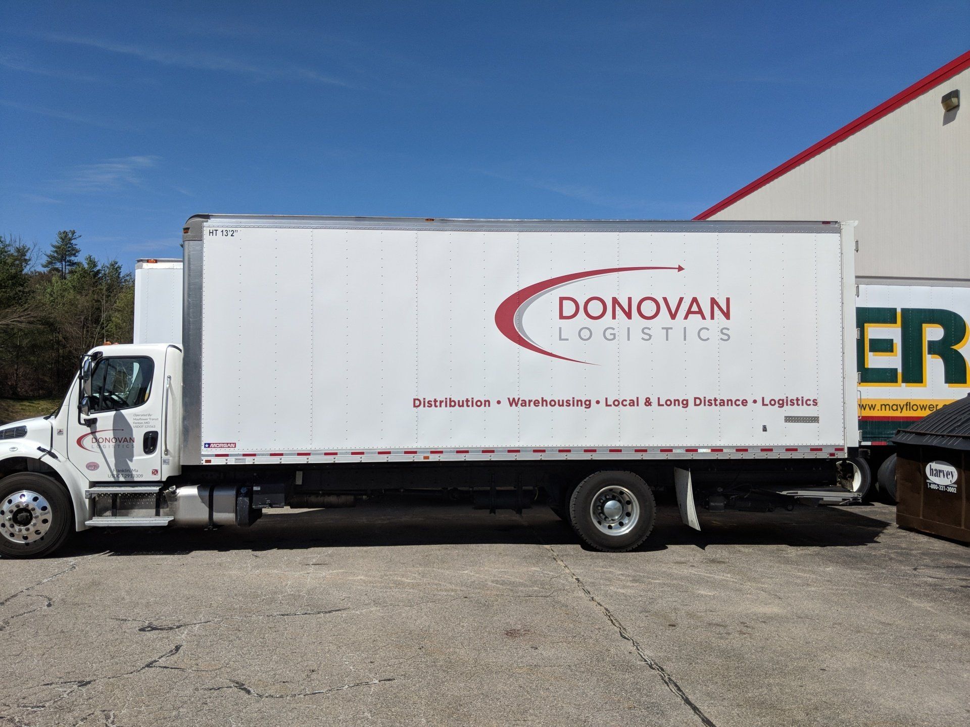 White Donovan Logistics box truck parked outdoors beside a warehouse under a blue sky