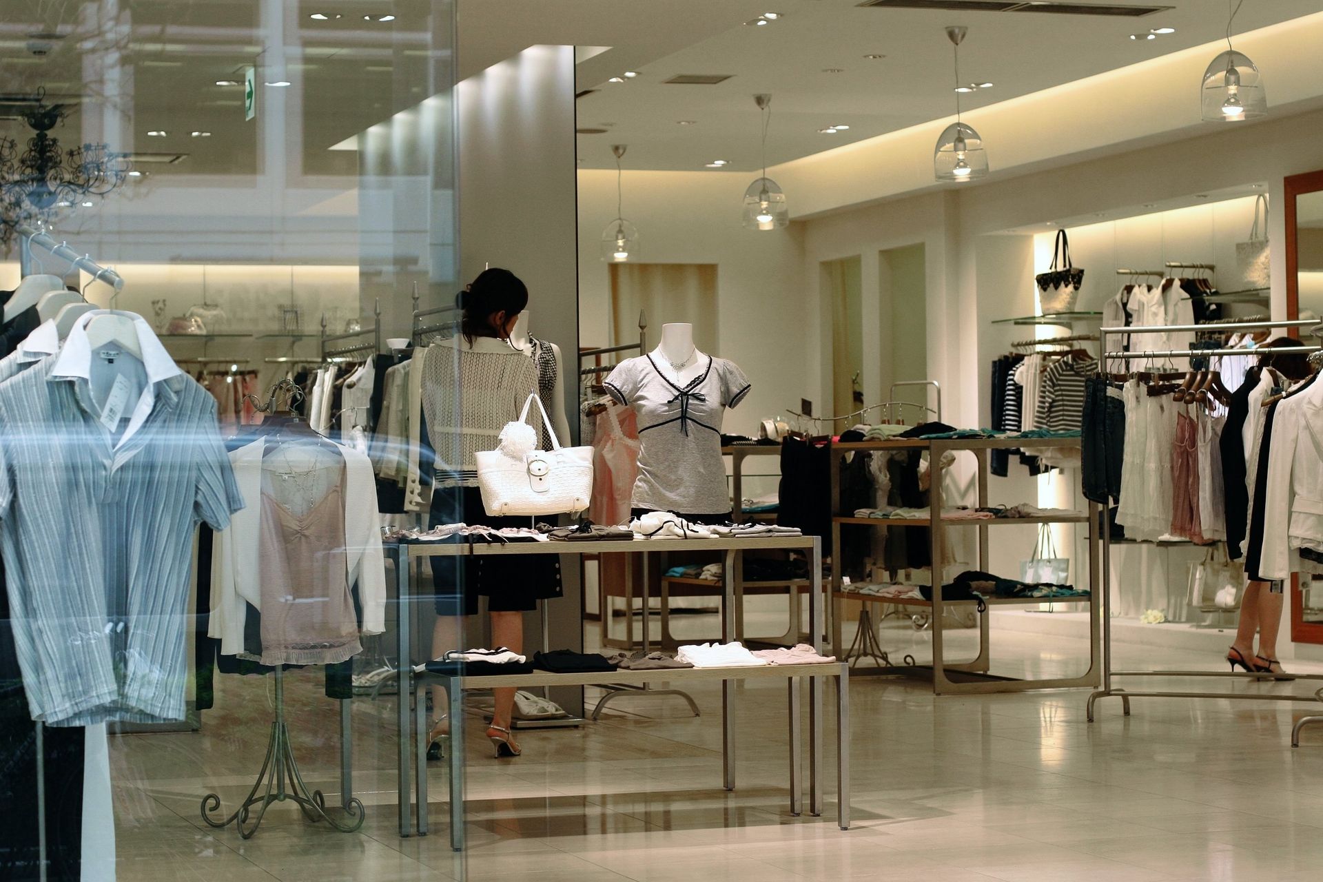 Clothing store interior with racks of shirts, dresses, and accessories on display.