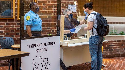A man is standing in front of a temperature check station.