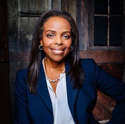 A woman in a blue jacket and white shirt is smiling for the camera.
