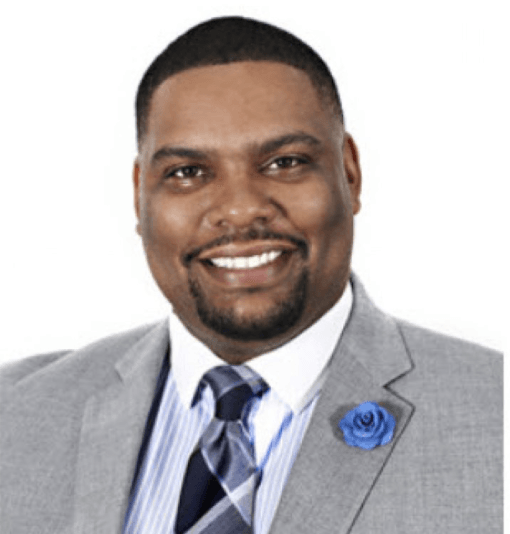 A man in a suit and tie is smiling for the camera