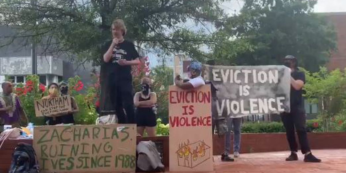 A group of people are protesting against eviction and holding signs.