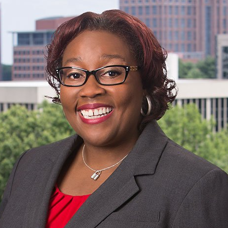 A woman wearing glasses and a red shirt is smiling for the camera.