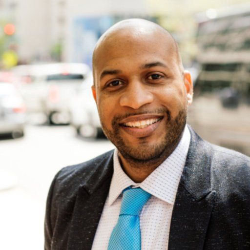 A man in a suit and tie is smiling for the camera