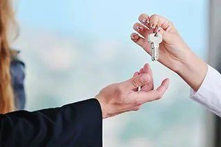 Woman Handing Man Set of Keys to Rental Property