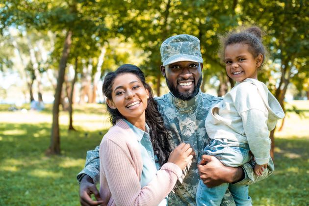 Man in Military Uniform Holding Wife and Daughter