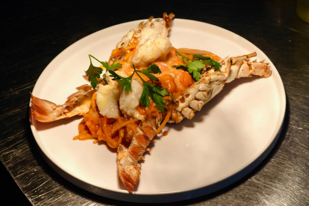 Une assiette blanche garnie de crevettes et de nouilles sur une table.