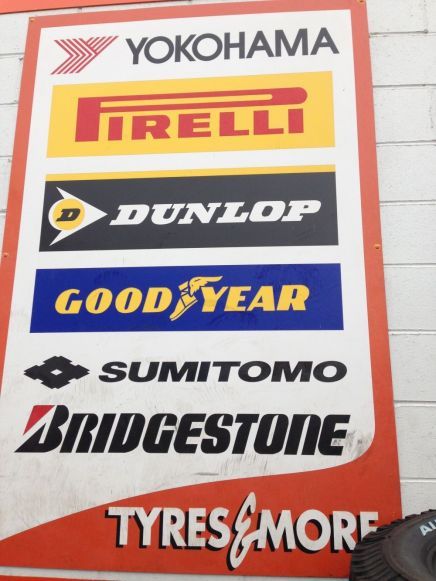 Sign with logos for Yokohama, Pirelli, Dunlop, Goodyear, Sumitomo, Bridgestone tires, and 