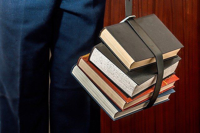 Student with books bundled by a belt.