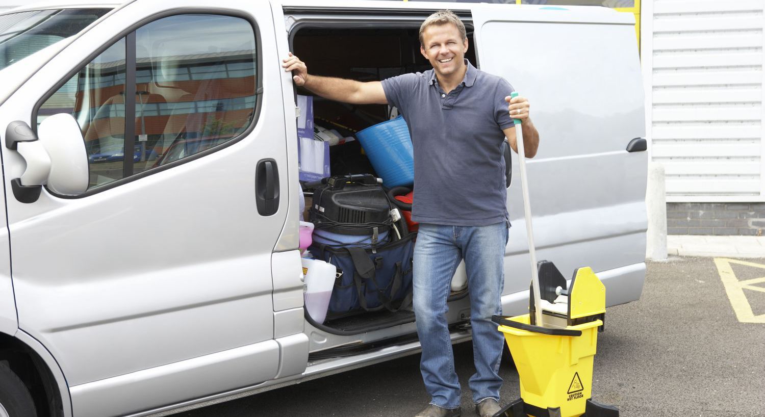 A commercial cleaning employee in Honolulu, HI smiling by his van