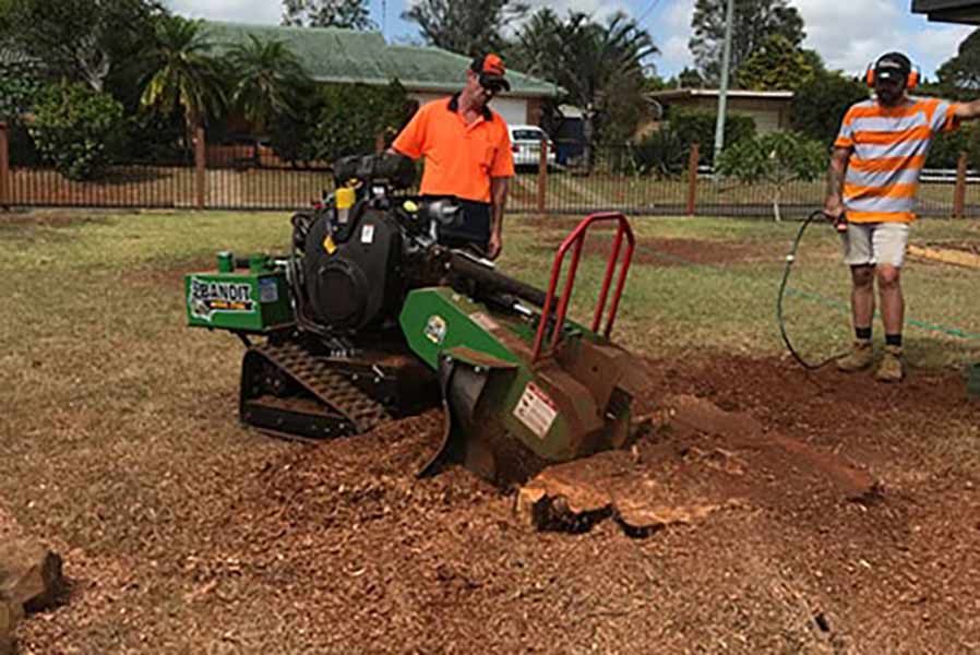 A Stump Grinder that is grinding a large stump in a field in Lismore