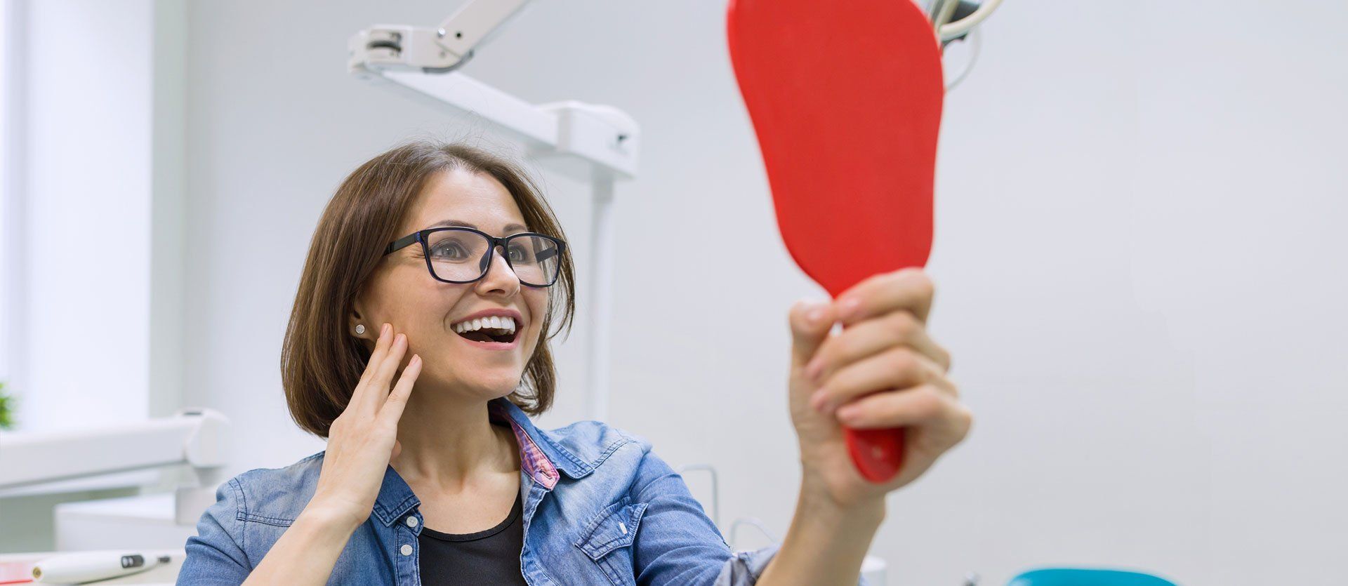 A woman is looking at her teeth in a mirror.