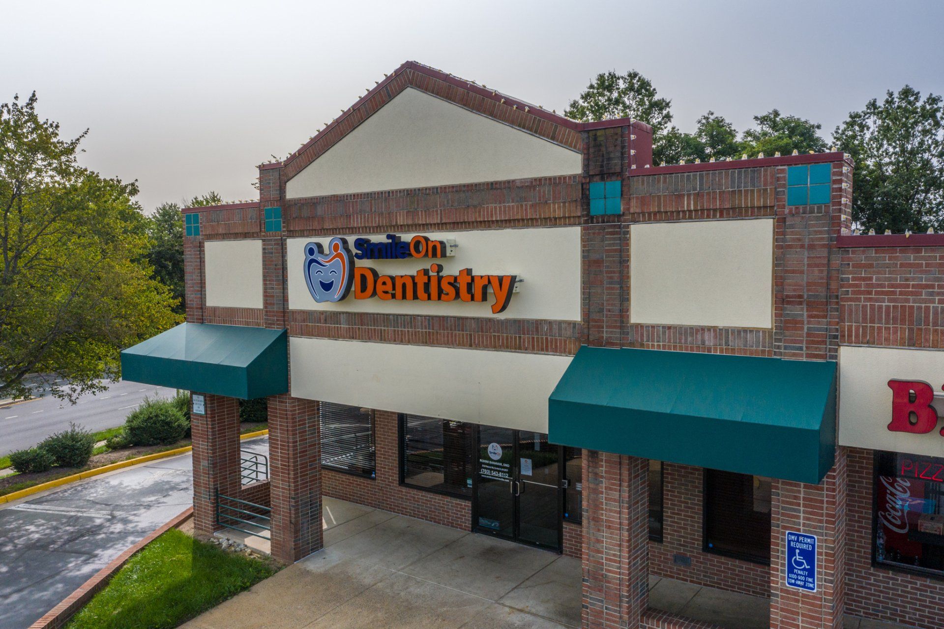 An aerial view of a dental office with a brick building and green awnings.
