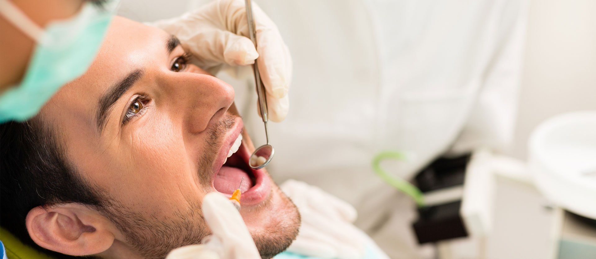 A man is getting his teeth examined by a dentist.