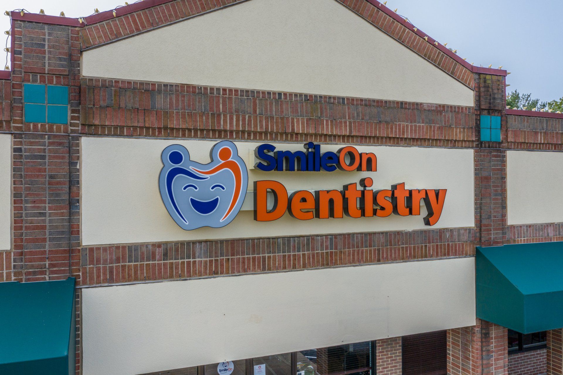 A smile on dentistry sign is on the side of a building.