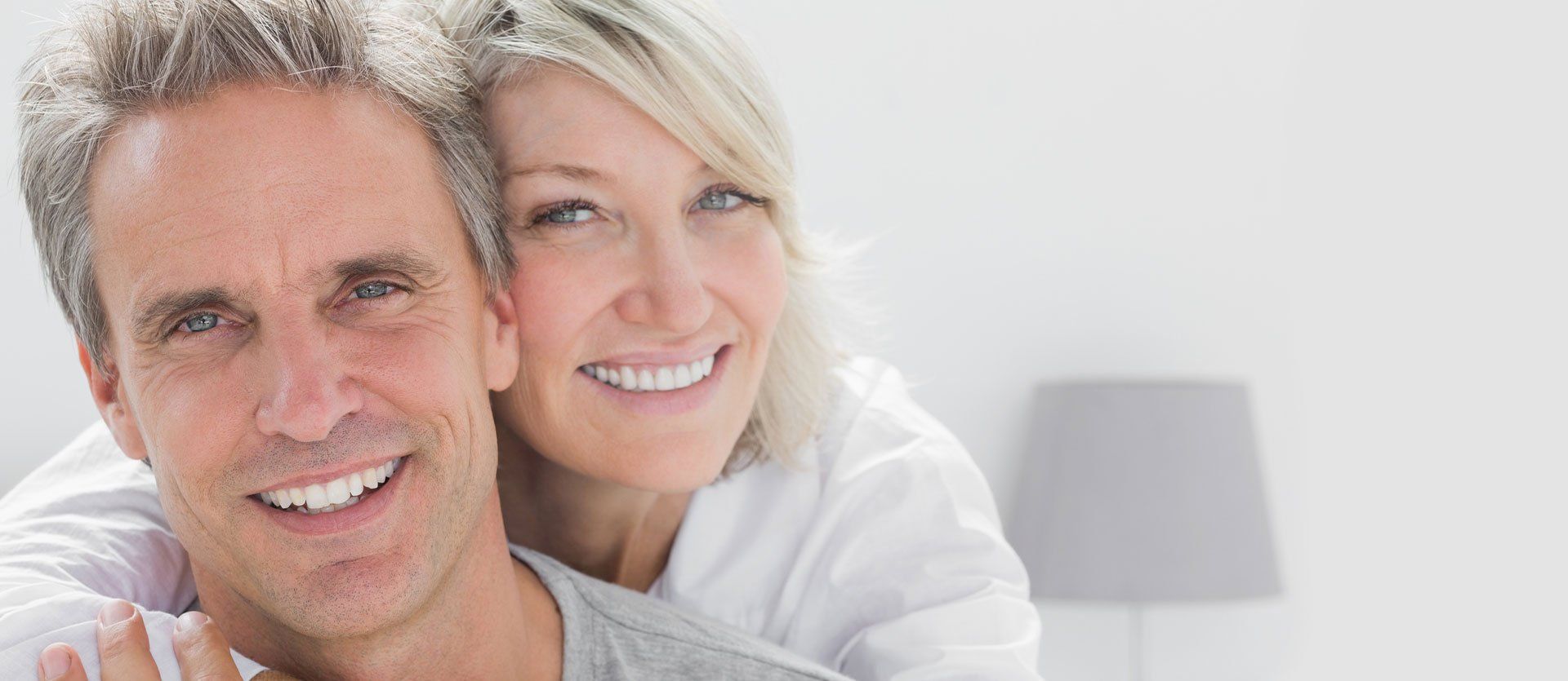 A woman is giving a man a piggyback ride and they are smiling for the camera.