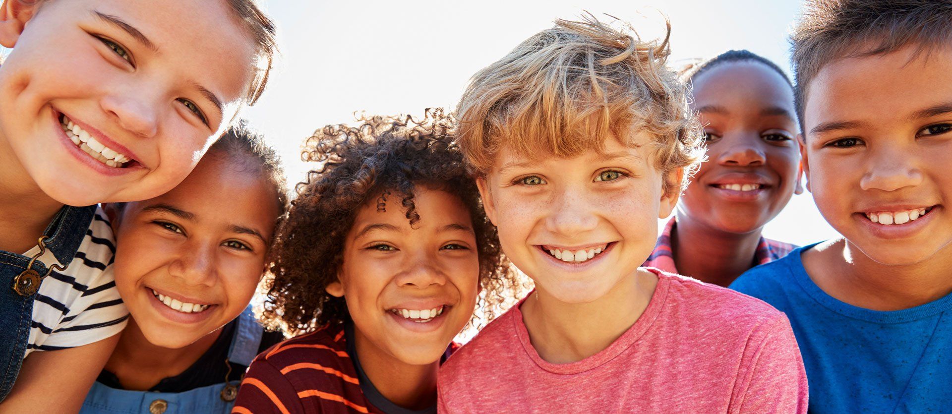 A group of children are posing for a picture together and smiling.