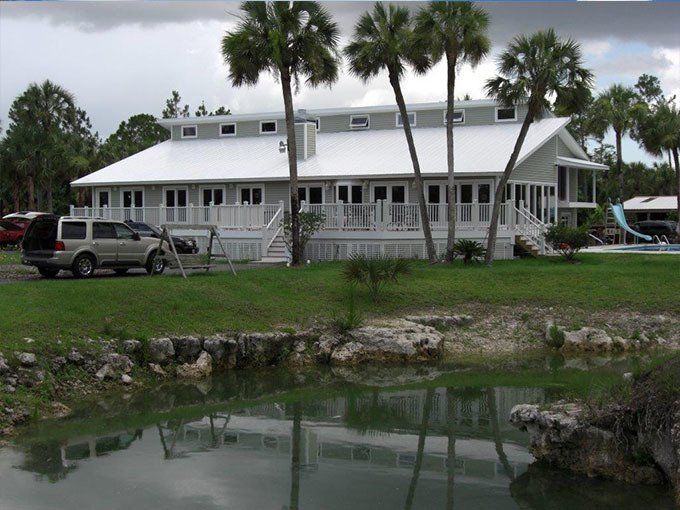 A large white house sits next to a body of water.
