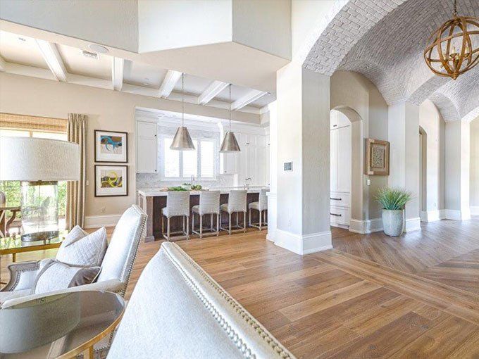 A living room filled with furniture and a kitchen with a wooden floor.