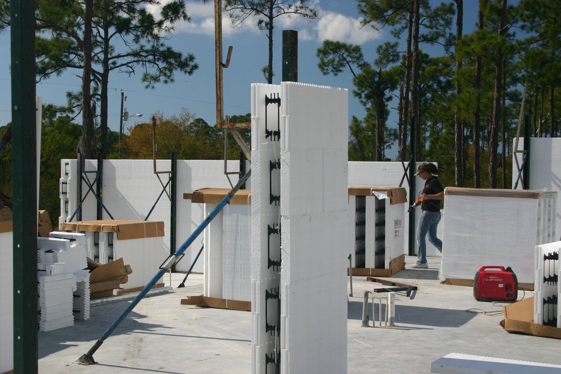 Construction site with insulated concrete forms. A person walks near a red generator.