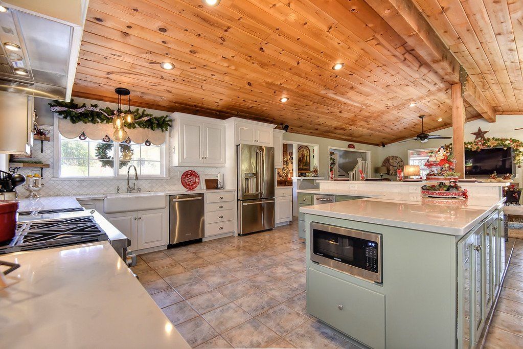 Spacious kitchen with white cabinets, stainless steel appliances, wood ceiling, and central island.