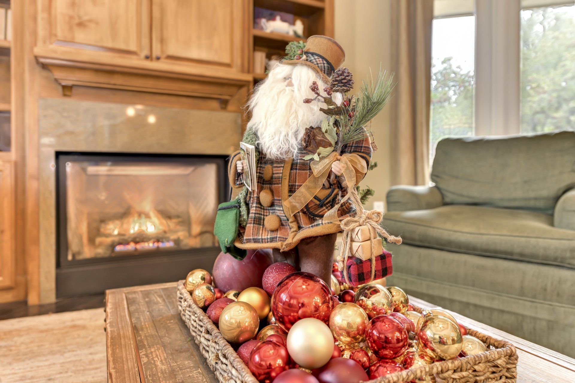 Santa decoration on a coffee table with ornaments, fireplace, and green couch in the background.
