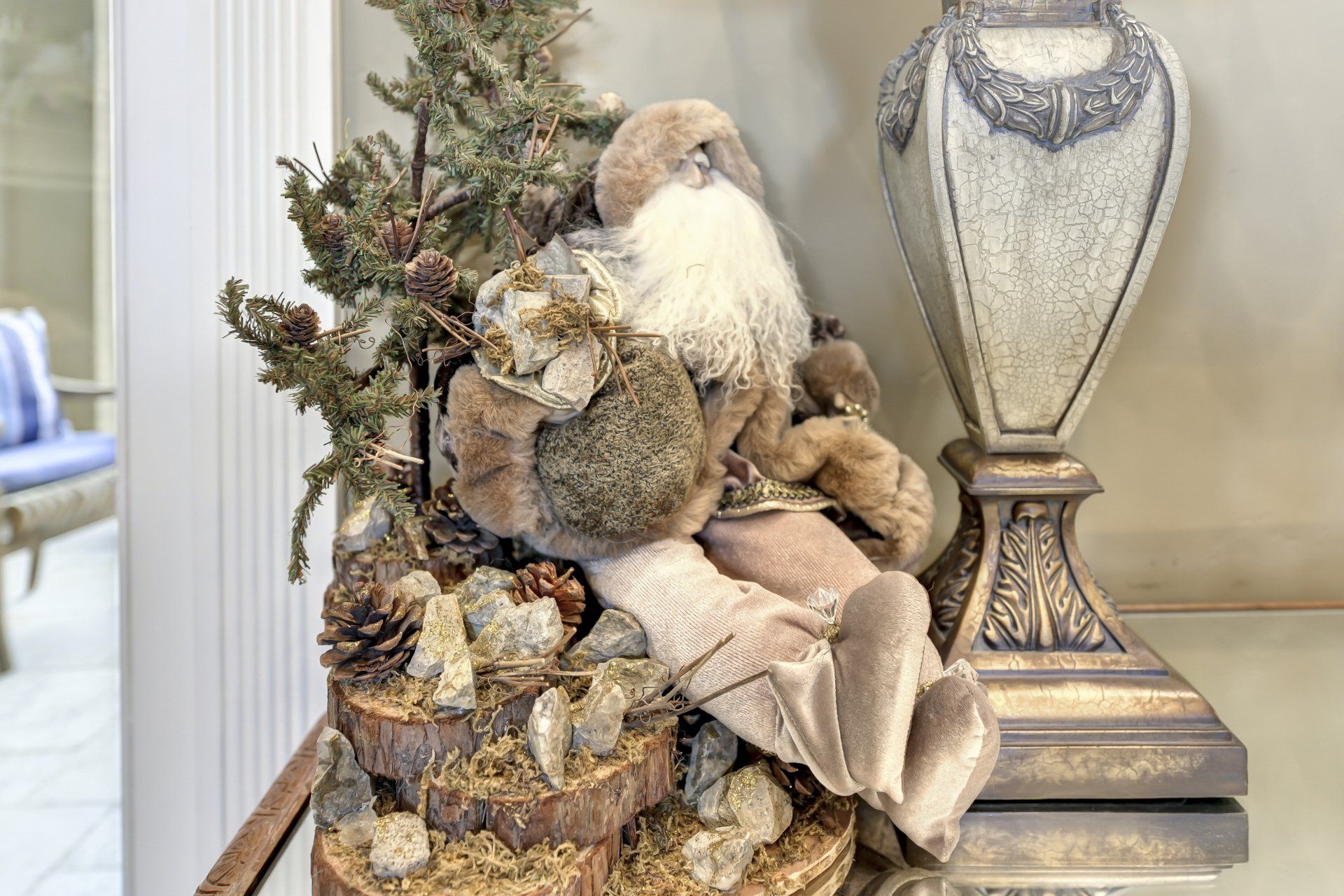 Santa Claus doll with fir tree and lamp on a table.
