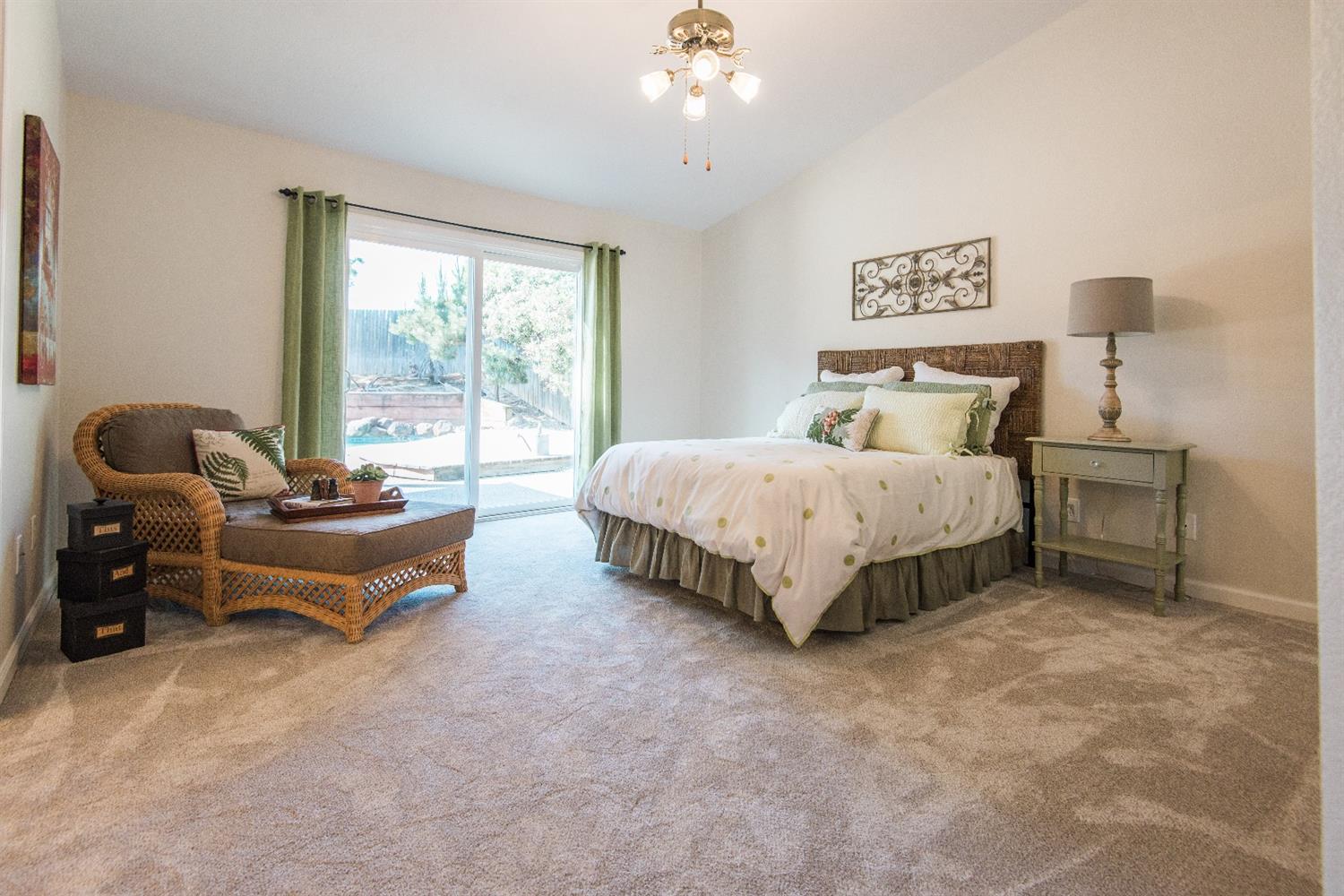 Bedroom with bed, chair, sliding door, and light-colored carpet.
