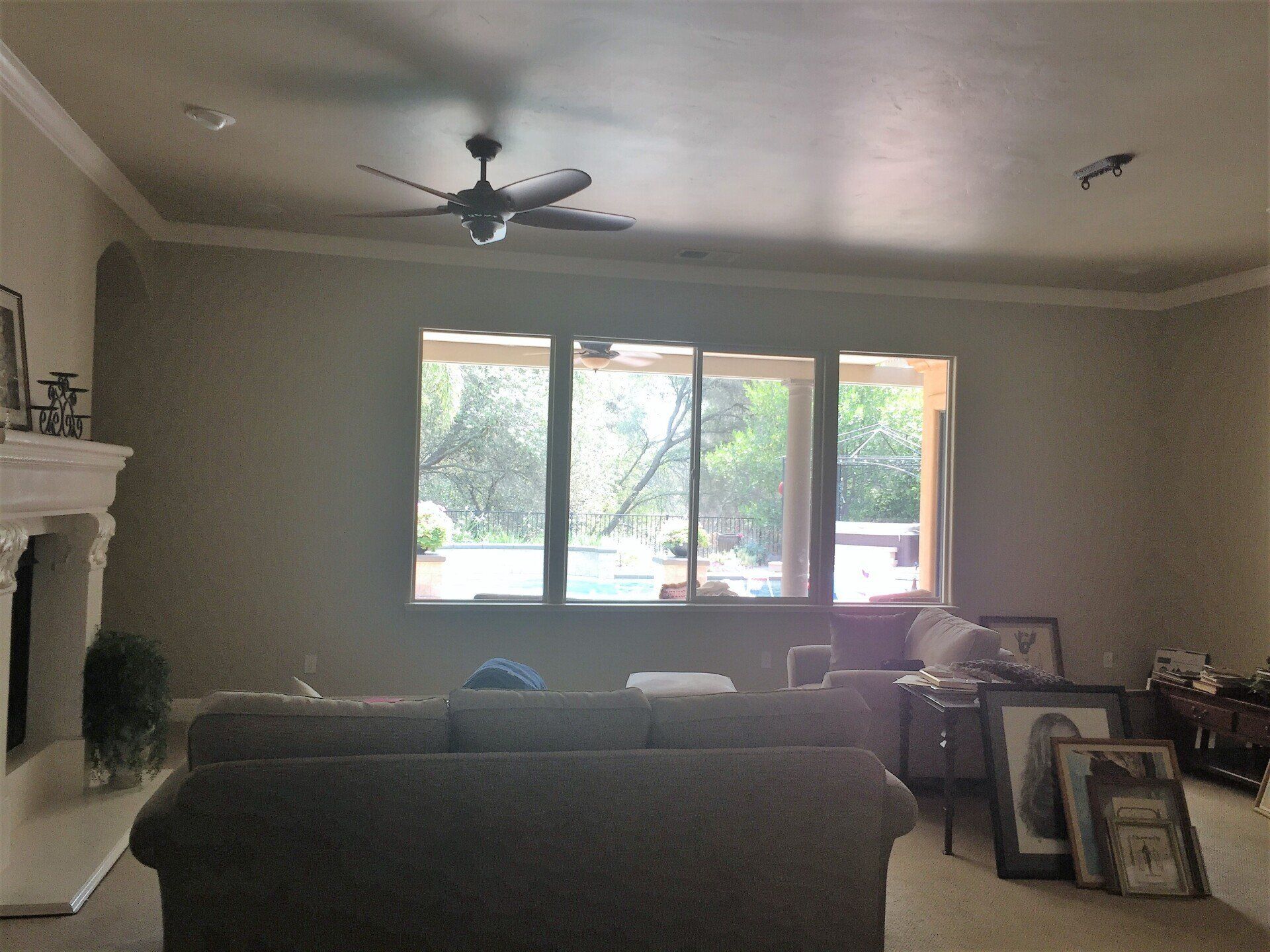 Living room with a sofa, window, fireplace, and ceiling fan.