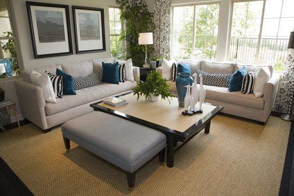 Living room with two gray sofas, blue pillows, a coffee table, and a large window.