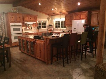 Rustic kitchen with wood cabinets, island with stools, and double ovens.