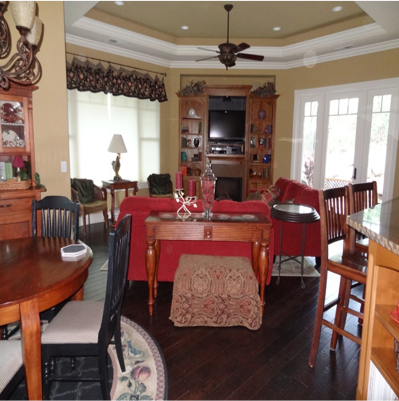 Open concept living and dining area with red couch, dark wood furniture, and windows.