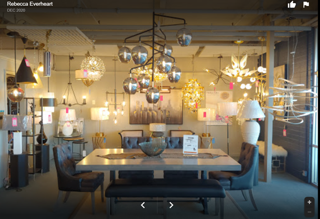 A showroom with diverse light fixtures. A dining table is centered with chairs and a bench.