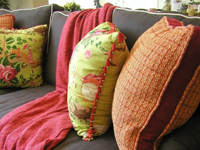 E-design Services Colorful patterned pillows and a red throw blanket on a gray sofa