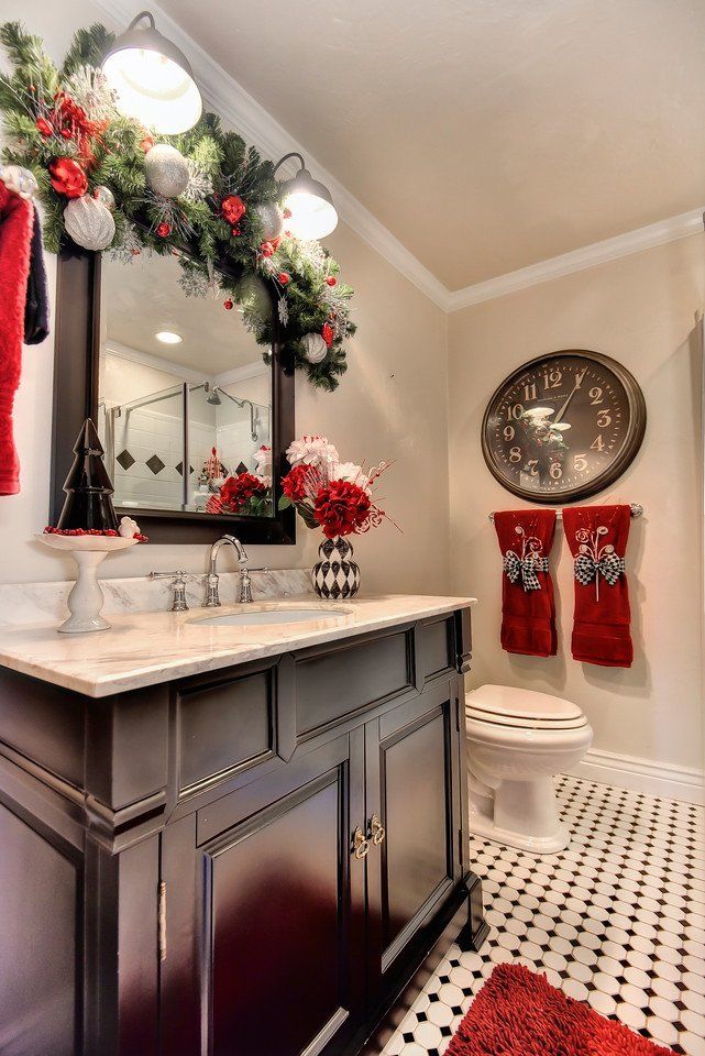 Christmas-decorated bathroom with garland, red accents, and a dark cabinet. A clock hangs on the wall.