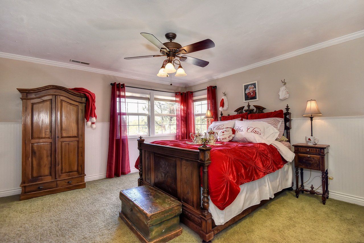 Bedroom with red bedding, wooden furniture, and green carpet.