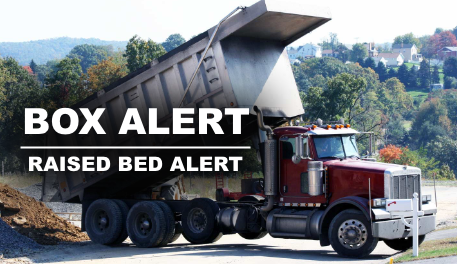 A red dump truck is driving down a road.