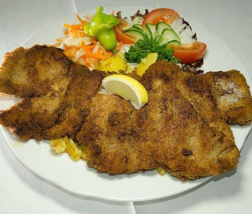 Ein weißer Teller mit gebratenem Fleisch und Gemüse
