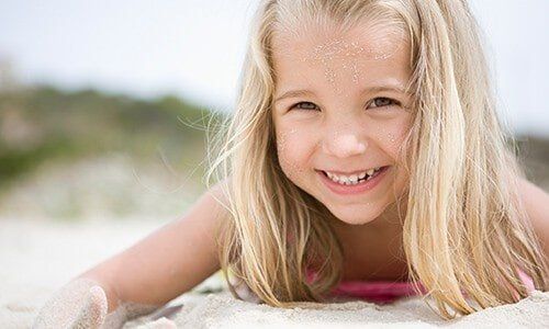 Young Girl Smiling in Sand - Oral Health in Pleasant Hill, MO Young Girl Smiling in Sand - Oral Health in Pleasant Hill, MO