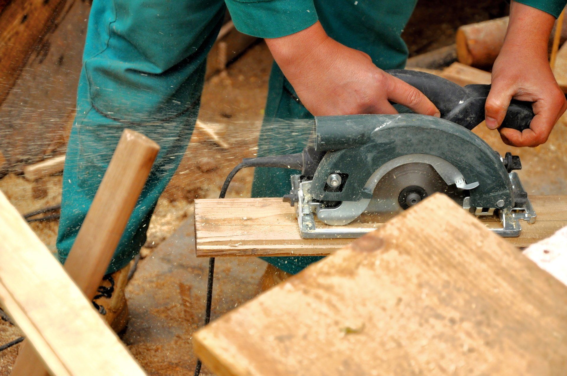 A man is using a circular saw to cut a piece of wood.