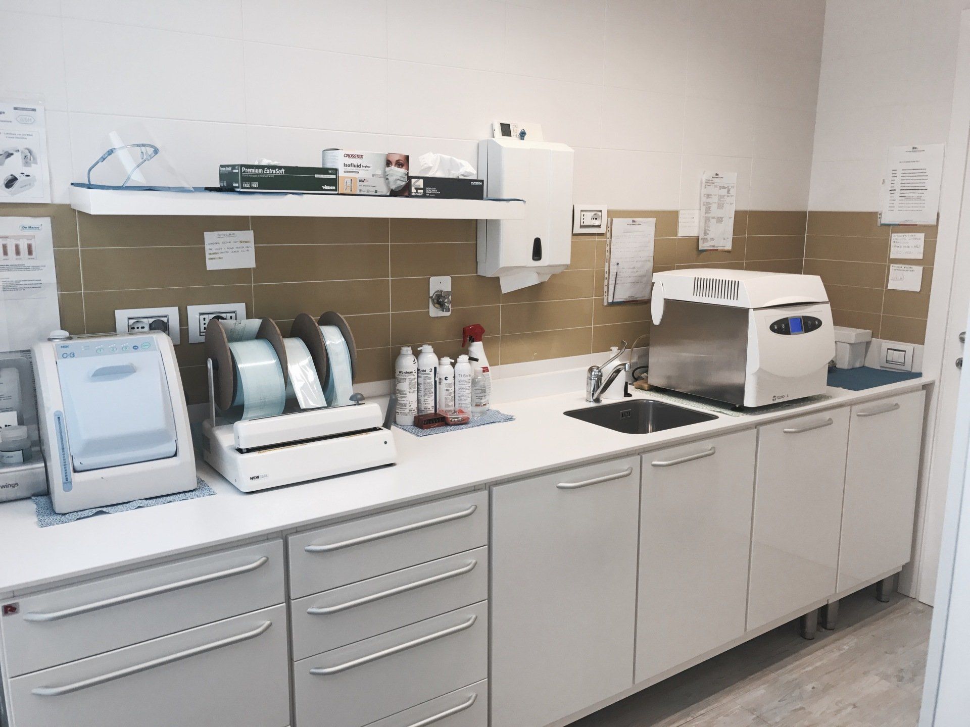 Bancone da laboratorio con attrezzatura medica, lavandino e armadietti.