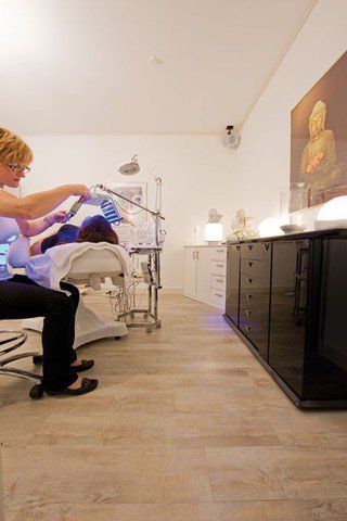 Eine Frau sitzt auf einem Stuhl, während eine andere Frau in einem Schönheitssalon eine Behandlung bekommt.