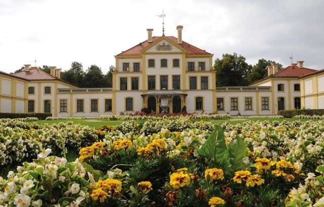 Ein großes weißes Gebäude mit einem roten Dach ist von Blumen umgeben