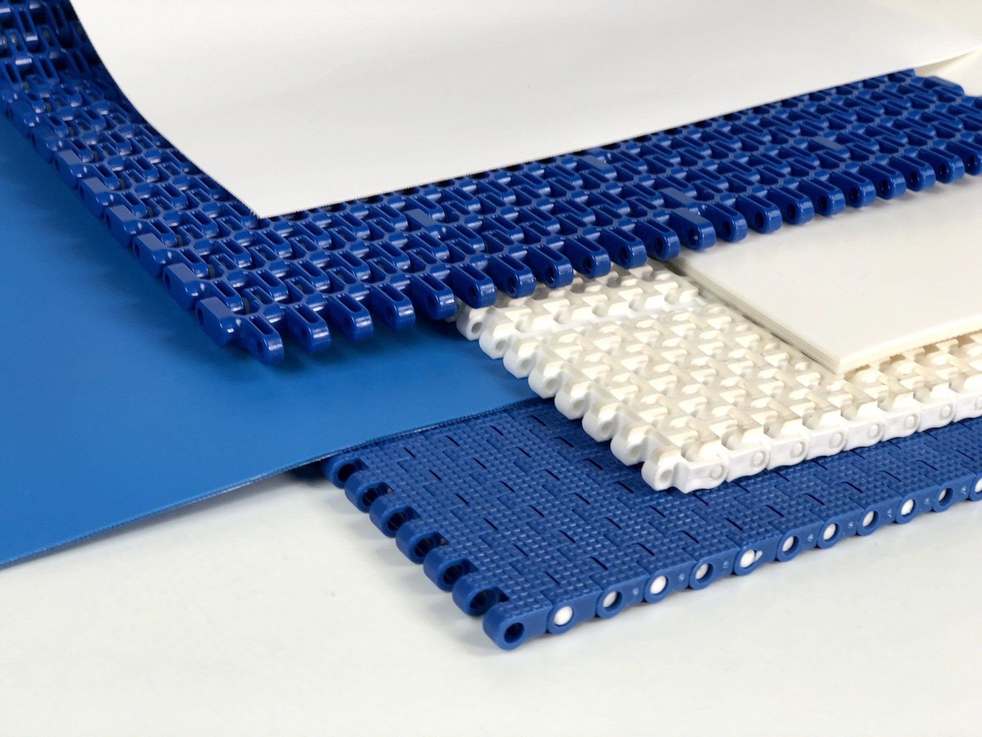 Muestras de cintas transportadoras en color azul y blanco, con distintas texturas: lisa, perforada y entrelazada.