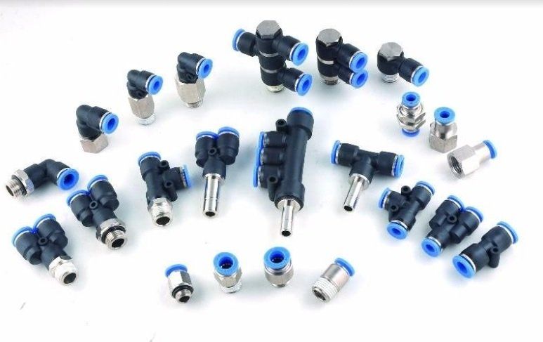 Surtido de accesorios neumáticos con componentes de plástico azul y negro sobre superficie blanca.